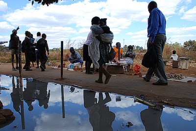 Residents of Kuwadzana in Harare walk past raw sewage.