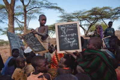 A Karimojong boy compares his results with the solutions on the blackboard.