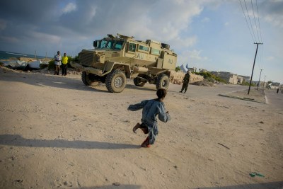 A Somali girl runs in front of an African Union armed personnel carrier in Mogadishu. In past months, residents of Mogadishu have enjoyed relative peace in their city after decades of instability.