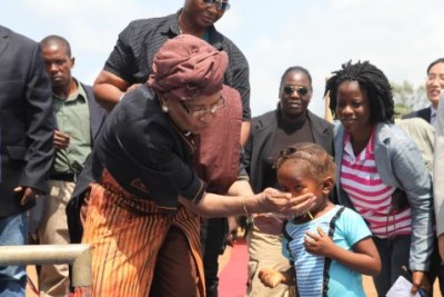 President Sirleaf quenches the thirst of a child shortly after dedicating a water pump.