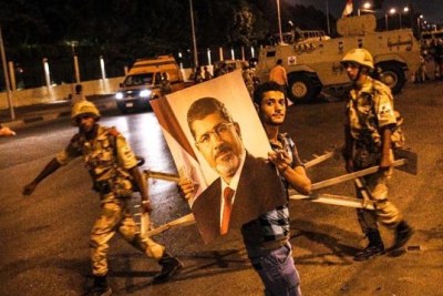 Un pro-Morsi qui défile devant des éléments de l'armée égyptienne avec le poster de son leader détenu par le régime militaire