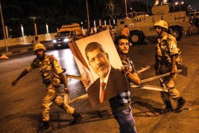 A supporter of ousted president Mohamed Morsi holds Morsi's picture passing in front of an army blockage near Raba'a Al-Adaweya square in Nasr city where thousands of Pro-Morsi protesters are still protesting in Cairo, Egypt on July 3, 2013.