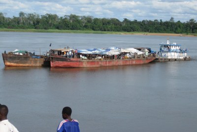 Un bateau flotte sur la rivière Oubangi en remorquant des barges.