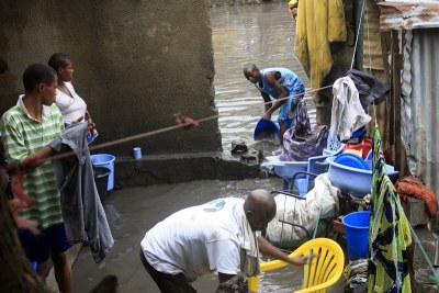 Une famille inondée par les eaux de pluie, tente de récupérer leurs biens en évacuant les eaux stagnantes dans la parcelle