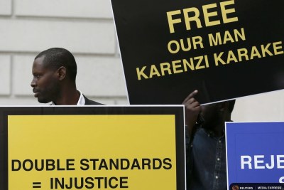 Des manifestants brandissant des pancartes pour exiger la libération du chef des services secrets Karenzi Karake du Rwanda, à l'extérieur du Tribunal d'instance de Westminster à Londres.