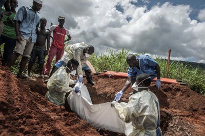Un enterrement d'Ebola à gauche debout dans la tombe, abaisse le corps d'une femme âgée dans un cimetière local.