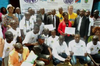 Mark Bristow and Jeanine Mabunda pose for a group photo after the graduation of 19 students from the driver training program conducted by INPP, in partnership with the OPR and Nos Vies en Partage.