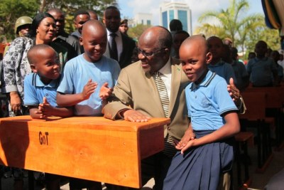 President John Magufuli shares a light moment with three Bunge Primary School pupils.