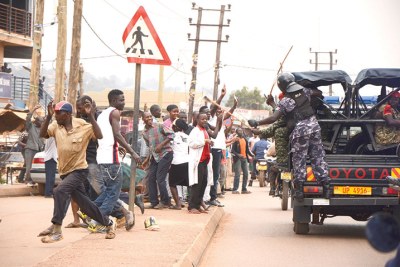 Stick-wielding policemen chase away people near Besigye’s car.