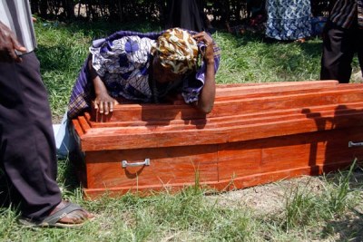 A woman weeps on the casket bearing remains of her relative outside Kasese Municipal Health Centre III mortuary.