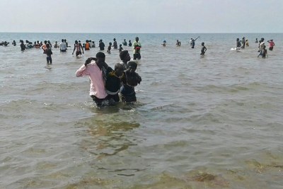 Saved. A survivor is helped ashore by rescuers as other rescuers continue to search for other victims in the lake on Sunday .