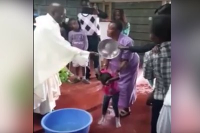 Catholic priest baptize children.
