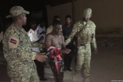 Somali security forces escort a man who was rescued from Pizza House.