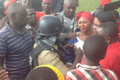 Winfred Kiiza, the leader of the opposition in parliament, centre,  struggles to control tears as she engages a police officer in Mbale after police officers fired teargas to disperse an age limit rally.