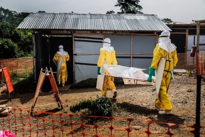 MSF staff members carry a deceased Ebola patient to the morgue in Kailahun, Sierra Leone. Death was always very present in Ebola Treatment Centres. Over 11,000 people died during this outbreak, and at several moments the morgues where overwhelmed. Sierra Leone, December 2014.
