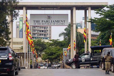 Guards and pedestrians stand outside the entrance to the parliamentary building in Kampala, Uganda’s capital.